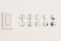 Ten identical 5 cm round acrylic mirror wall stickers beside a light switch