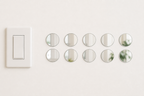 Ten identical 5 cm round acrylic mirror wall stickers beside a light switch