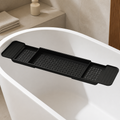 Matte black three-piece telescoping bathtub bridge tray spanning a white tub