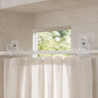 Two transparent self-adhesive spring clamps holding a slim white curtain rod