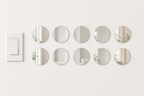 Ten identical 8 cm round acrylic mirror wall stickers beside a light switch