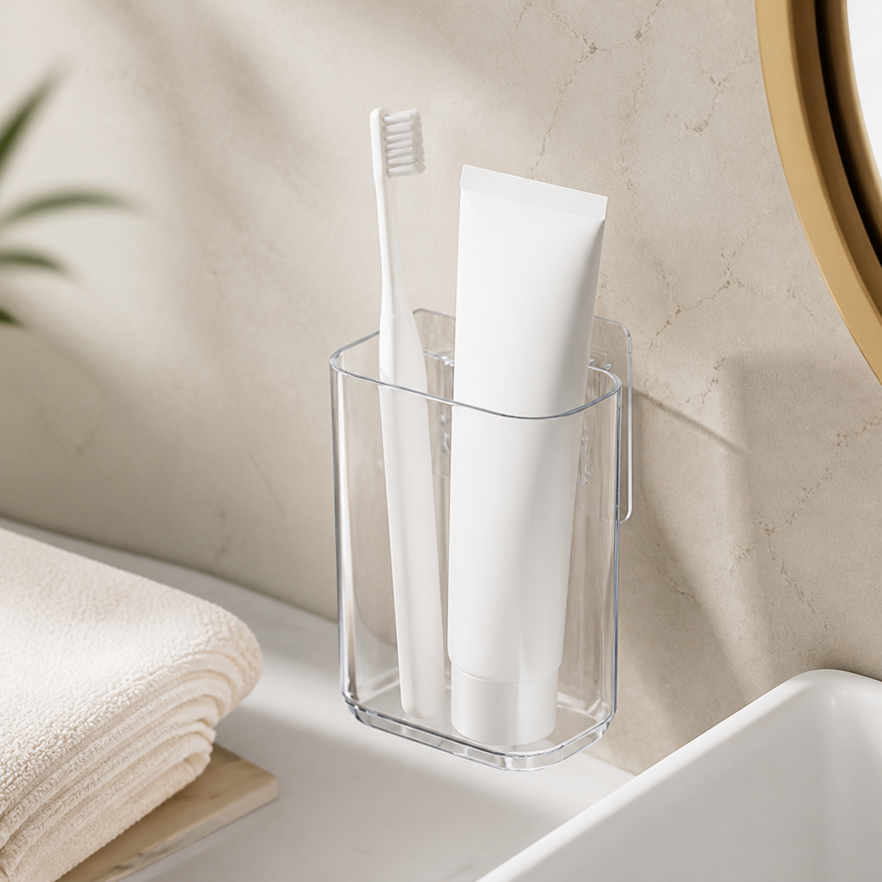 Transparent single-compartment toothbrush cup mounted beside a warm neutral vanity