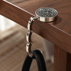 Close view of the articulated silver links on an ornate black floral purse table hook