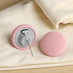 Close-up of the pink fabric button and gray hinged locking mechanism with attached metal pin