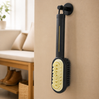 Black suede shoe brush hanging by its loop with cream grooved face and thin gold handle accent visible
