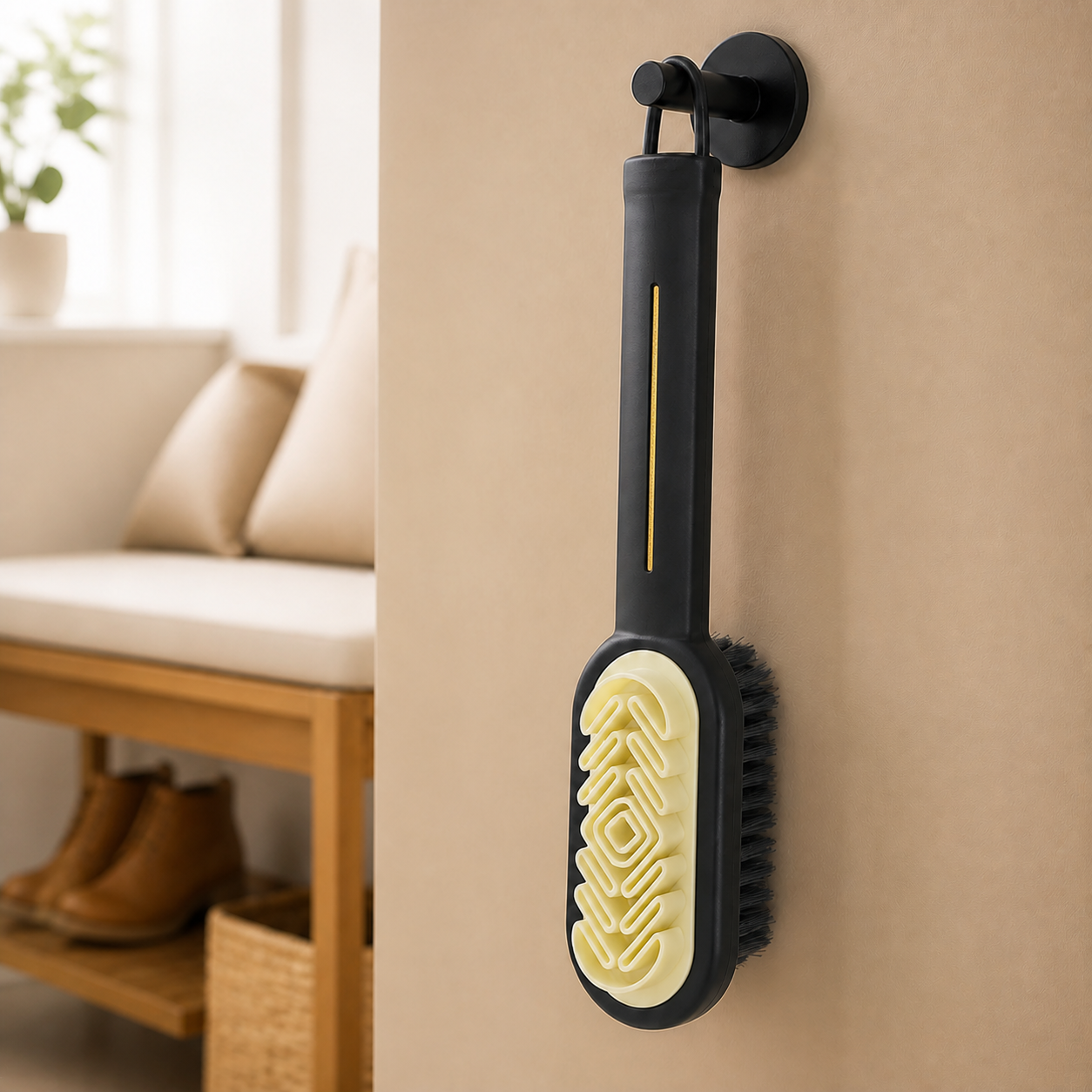 Black suede shoe brush hanging by its loop with cream grooved face and thin gold handle accent visible