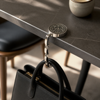 Ornate black floral purse hook holding a black handbag from a dark restaurant table