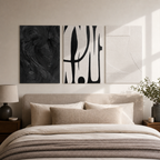 Minimalist black and white abstract canvas set of three displayed unframed above a warm neutral bed