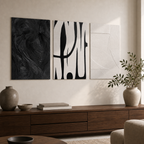 Three unframed black and white abstract canvas prints above a walnut console in a warm living room
