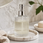 Cozy Haven clear ribbed glass soap dispenser on a vanity tray close-up
