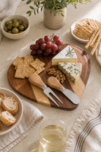 Heart-shaped acacia cheese board with crackers, grapes, cheese, and cutlery
