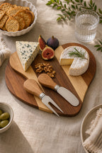 Heart-shaped acacia cheese board set with cheese and fruit on a dining table