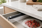 Black kitchen wrap dispenser with cutter in a kitchen drawer