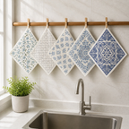 Five blue and gray patterned reusable cleaning cloths hanging above a kitchen sink
