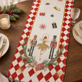 Nutcracker print linen table runner with red diamond border on a walnut dining table