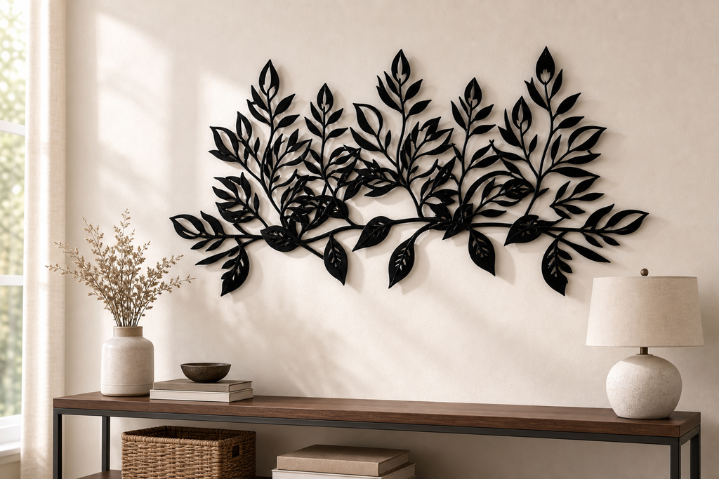 The leaf branch spanning a pale plaster wall, leaves standing proud and casting soft shadows
