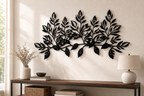 The leaf branch spanning a pale plaster wall, leaves standing proud and casting soft shadows